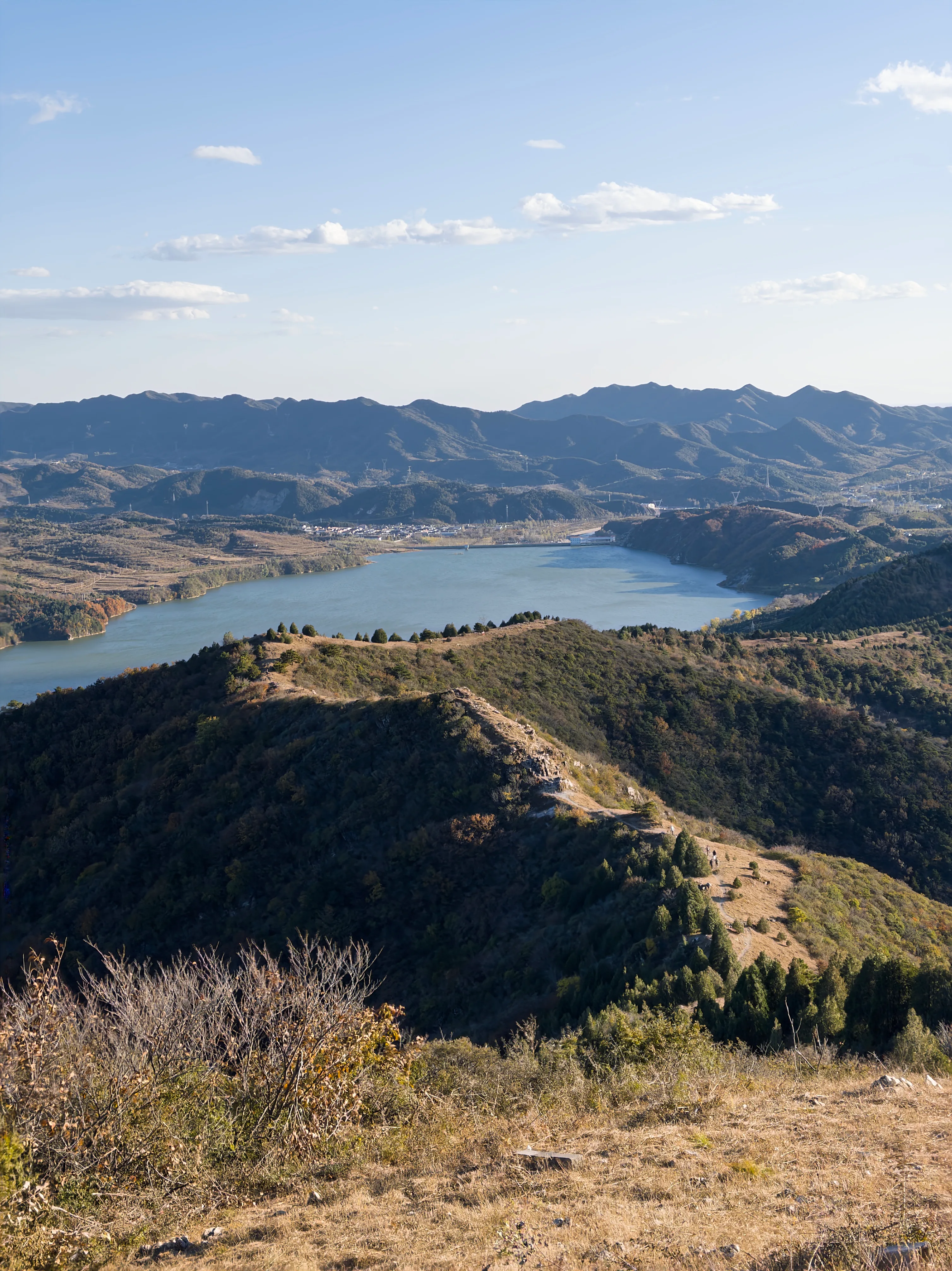 竖幅视角沿城墙回望群山，山谷与水面在脚下展开。